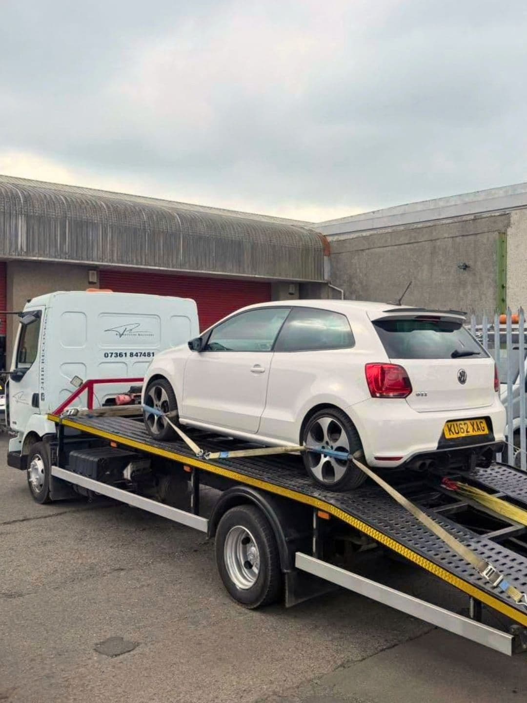 White Volkswagen secured on a Robertsons recovery flatbed, viewed from the rear